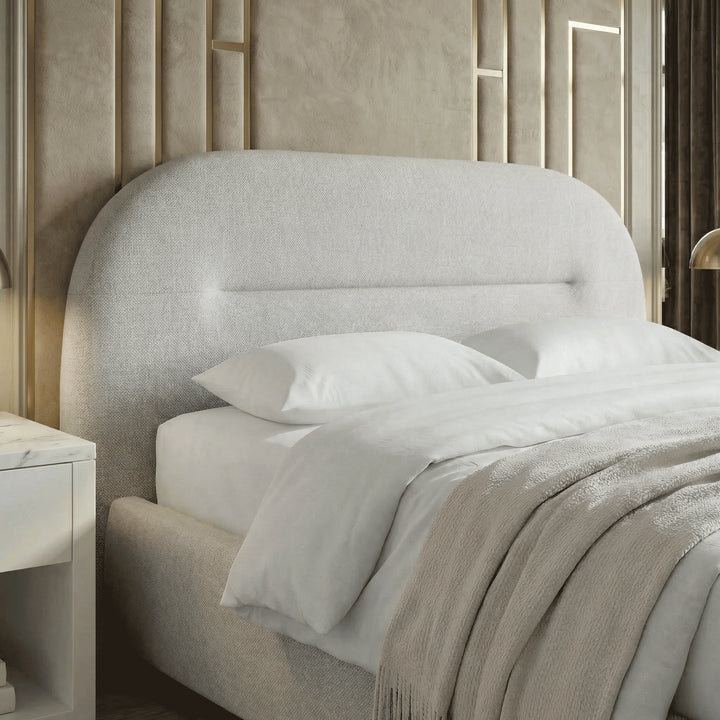 [Grey | King] Close crop of upholstered headboard with channel seam against ornate gold moulding panels and brass lamp glow