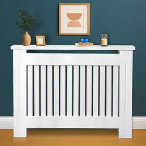 Medium Chelsea White Radiator Cover with vertical slats, styled in a modern room setting with decorative top shelf.