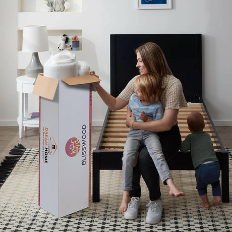 Family unboxing a Blisswood memory foam mattress king size in a modern bedroom.