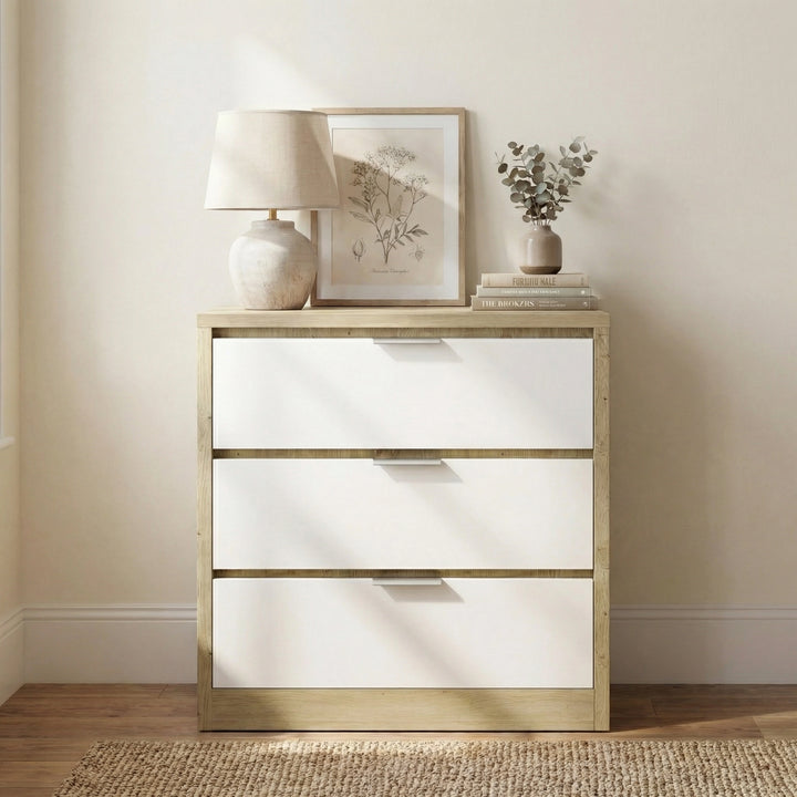 [Oak+White] Skova chest of drawers face-on against cream wall, sunlight crossing the white drawer fronts