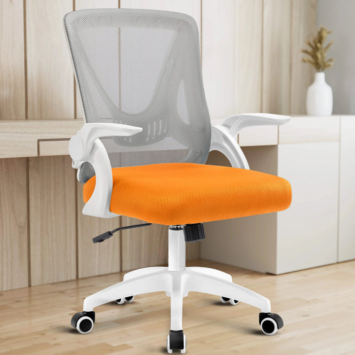 [Grey + Orange] Grey and orange mesh chair placed in a home office setup, offering ergonomic seating with the desk in backdrop