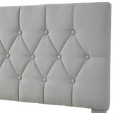 Close-up of a modern luxury bed frame with a tufted grey upholstered headboard.