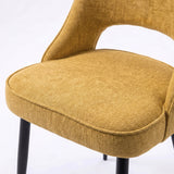 [Mustard | Set of 2] Comfy dining chair close-up view of seat, piped edge, curved open back and black metal legs.