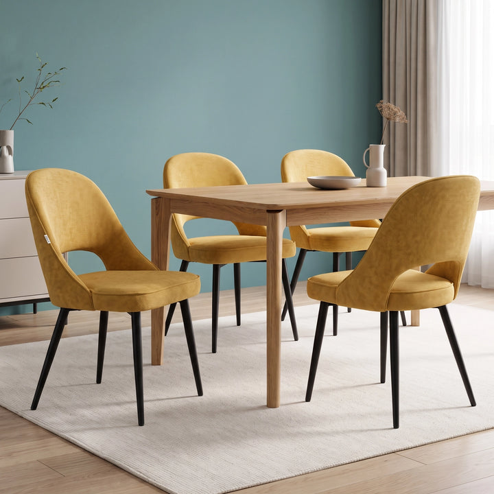 [Mustard | Set of 4] Four curved-back fabric dining chairs styled around a wood table with black legs, a bowl and jug.