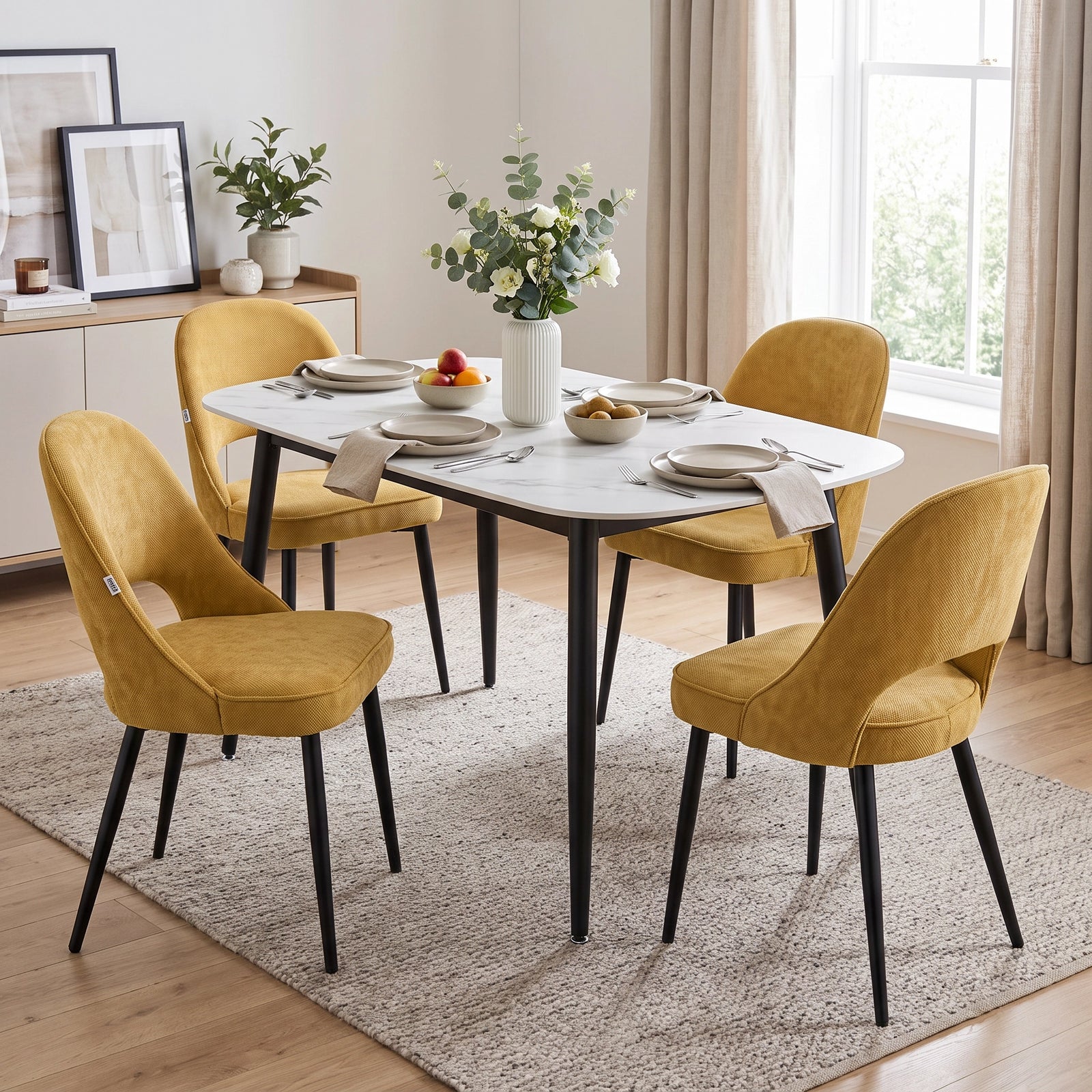 [Mustard | Set of 2] Two pairs of the comfy dining chairs at a white marble-effect table styled with fruit and flowers.
