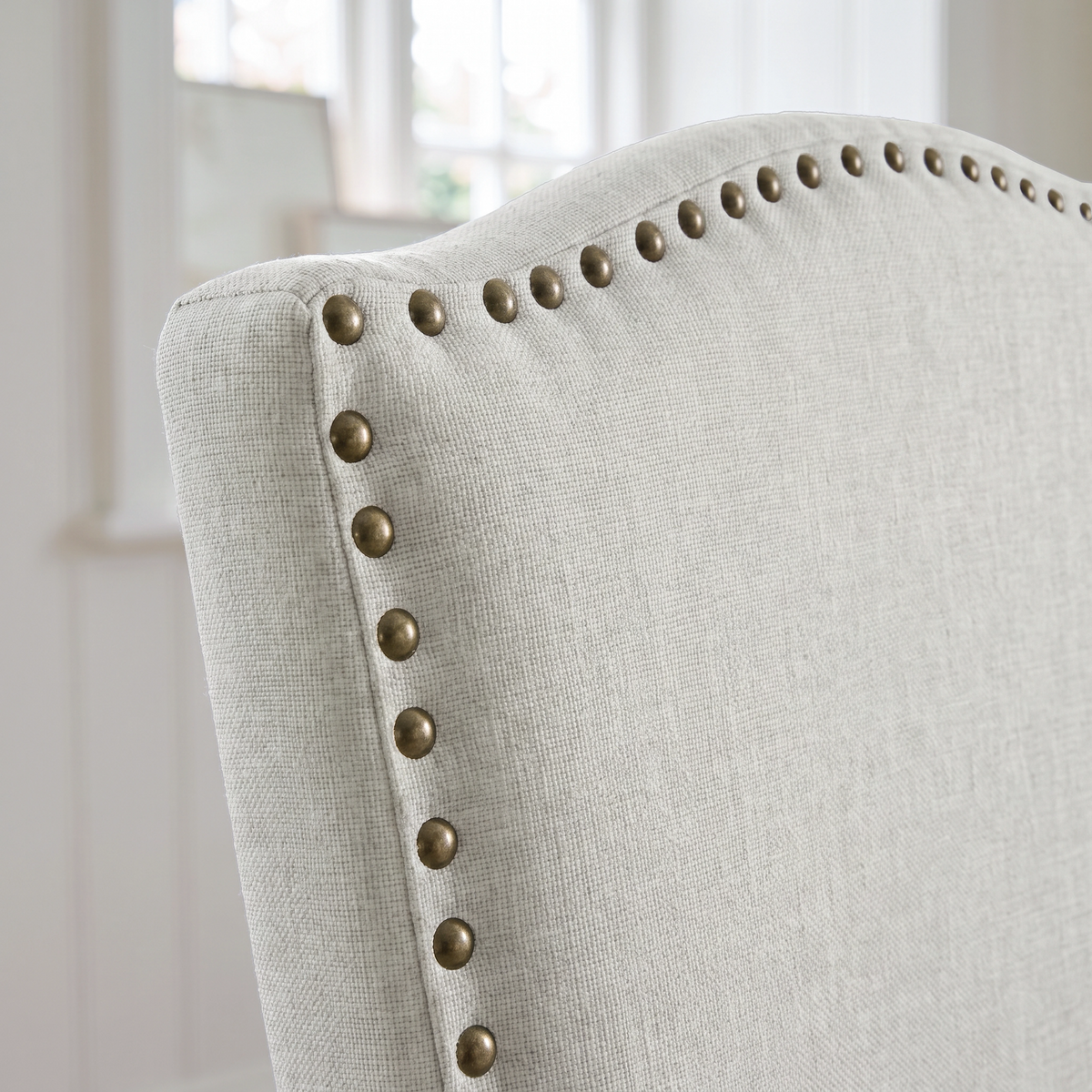 [Beige | Set of 2] Close-up of curved high back with fabric upholstery and bronze nailhead trim