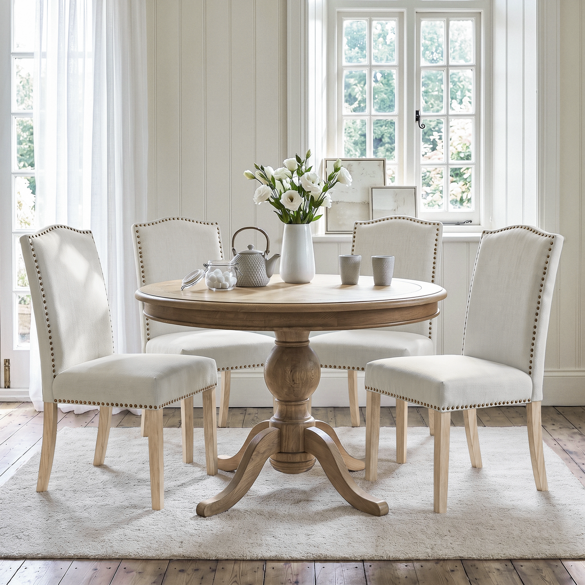 [Beige | Set of 4] Four nailhead dining chairs shown around a round wooden dining table in a dining room
