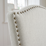 [Beige | Set of 4] Close-up of curved high back with fabric upholstery and bronze nailhead trim