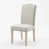 [Beige | Set of 4] Nailhead dining chair beside a round wooden table in a bright dining room