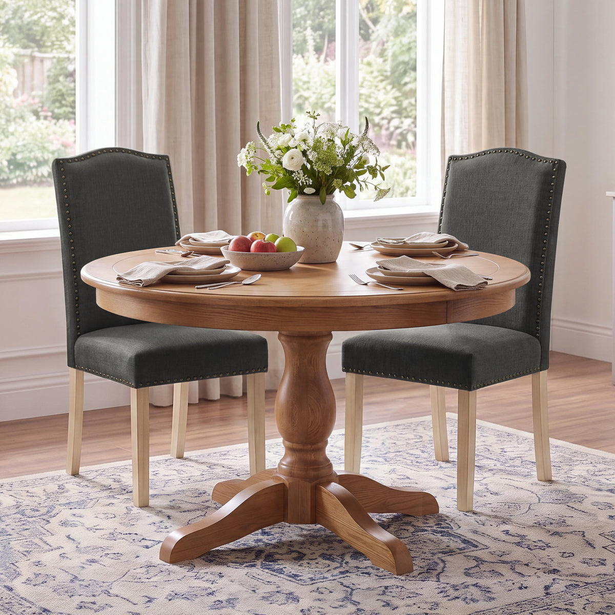[Dark Grey | Set of 2] Two nailhead dining chairs shown around a round wooden dining table in a dining room
