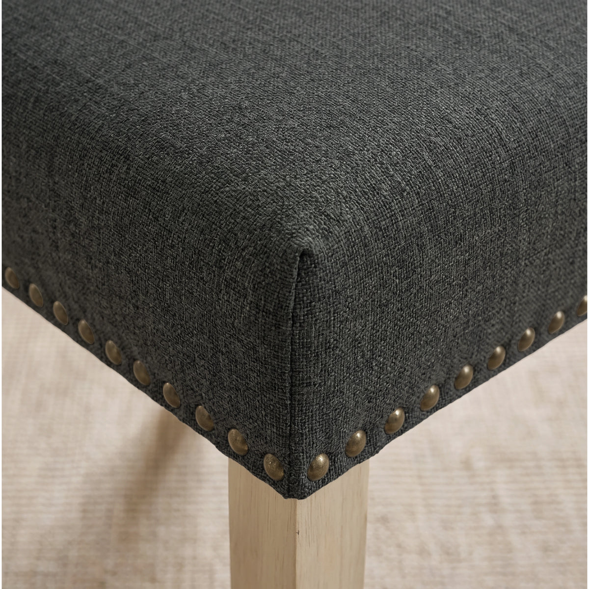 [Dark Grey | Set of 2] Close-up of fabric seat, bronze nailhead trim and light wooden leg on the dining chair