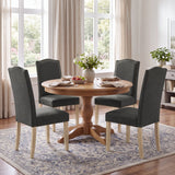 [Dark Grey | Set of 4] Four nailhead dining chairs shown around a round wooden dining table in a dining room
