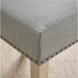[Light Grey | Set of 4] Close-up of fabric seat, bronze nailhead trim and light wooden leg on the dining chair