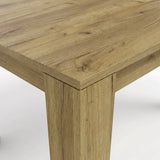 [Oak] Close-up of the oak-effect tabletop corner and thick L-shaped leg; natural-looking grain covers both surfaces.