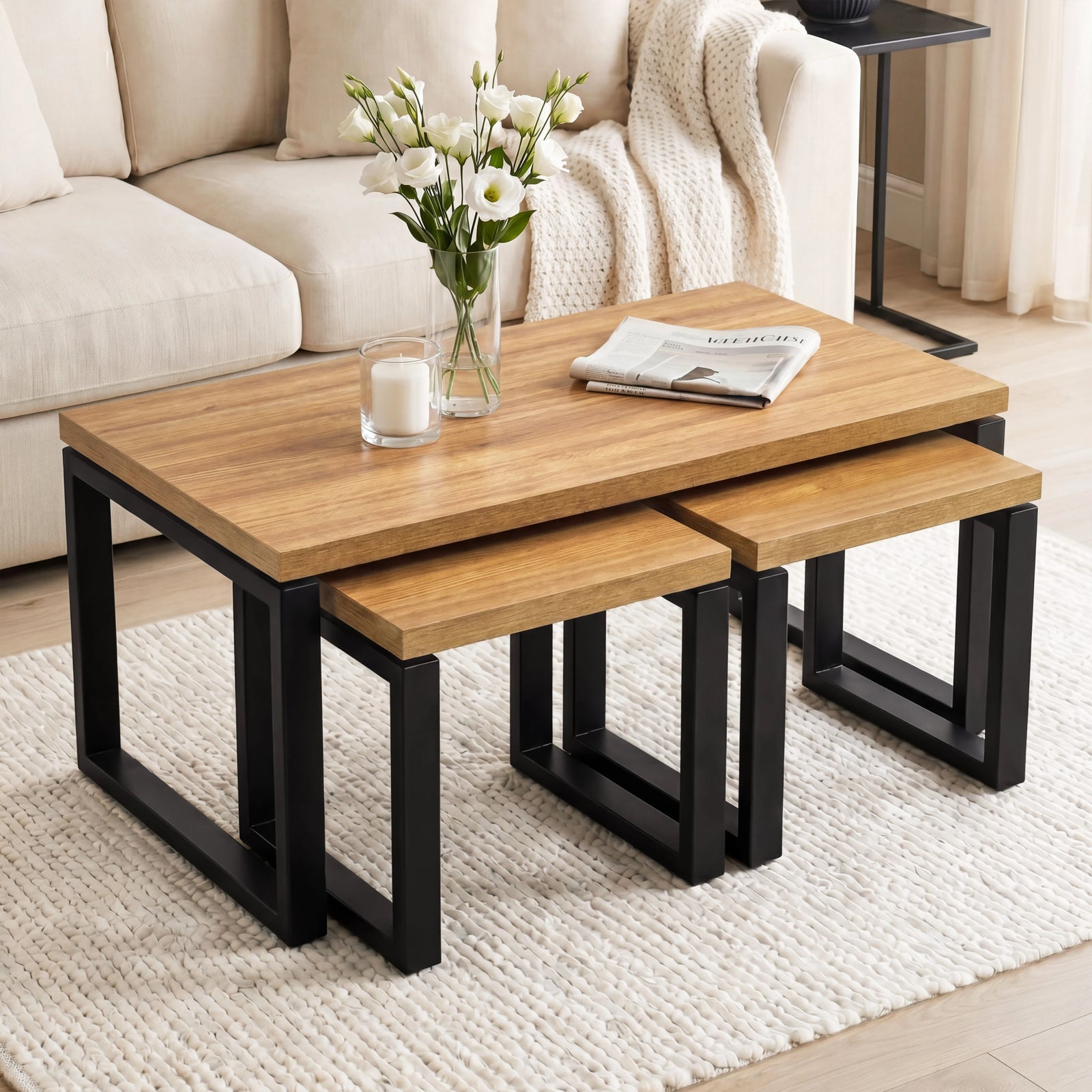 [Oak Effect] Nestline coffee table set beside a cream sofa, with flowers, books, and nesting side tables pulled outwards