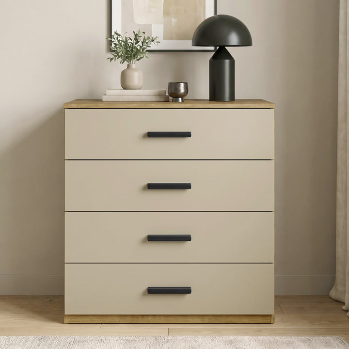 [Oak+Cashmere] Front view of a modern oak frame and beige 4-drawer chest with black handles styled against a neutral room wall