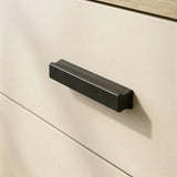 [Oak + Cashmere] Close view of black wooden handle mounted on cashmere drawer front framed by oak wood texture