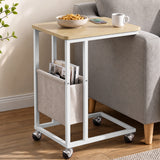 [Oak] sofa side table side view with oak-effect top, storage pouch, snacks and wheeled C-shaped base