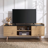 [Oak] modern wooden TV stand with a black top surface, styled with a black-screen TV, decorative items, and a stereo receiver, set against a white paneled wall.