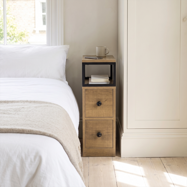 [Oak] Narrow side table with storage beside a bed, holding a lamp and small bedroom essentials