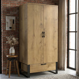 [Oak Effect] Rustvale wardrobe angled view with closed double doors, lower drawer, black handles, brick wall, and window.