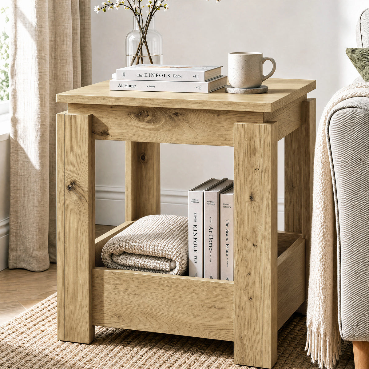 [Oak] Angled view of the square side table beside a sofa, with books and a folded throw in the open lower storage