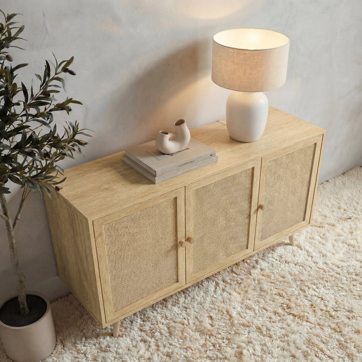 [Oak Effect] Wovena 3 door rattan sideboard seen from above with a lit lamp, two books and a small figurine on top