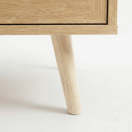 [Oak Effect] Wovena close-up of a solid tapered natural oak leg showing fine wood grain detail where it meets the clean mitre-edged cabinet base corner