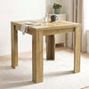 [Oak] Close-up closed wood-grain tabletop, steel hinges, wide legs, black mug, water glass, plate and napkin