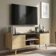 [Oak] Larvik styled at an angle in a sage green living room with wall-mounted TV, books, plants, vases, and grey armchair