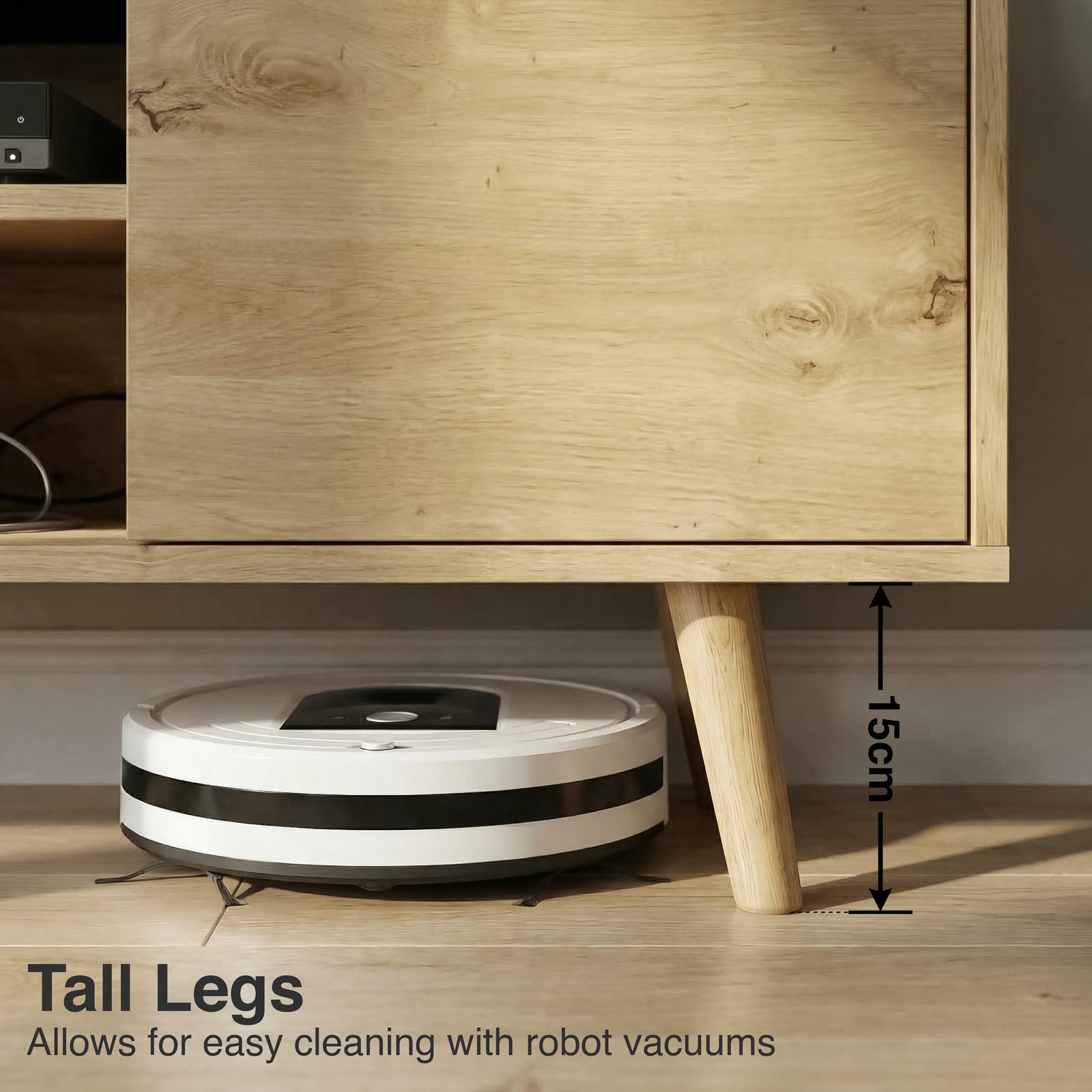 [Oak] Larvik close-up of 15cm tapered oak legs with robot vacuum passing underneath on wooden floor in warm-toned room