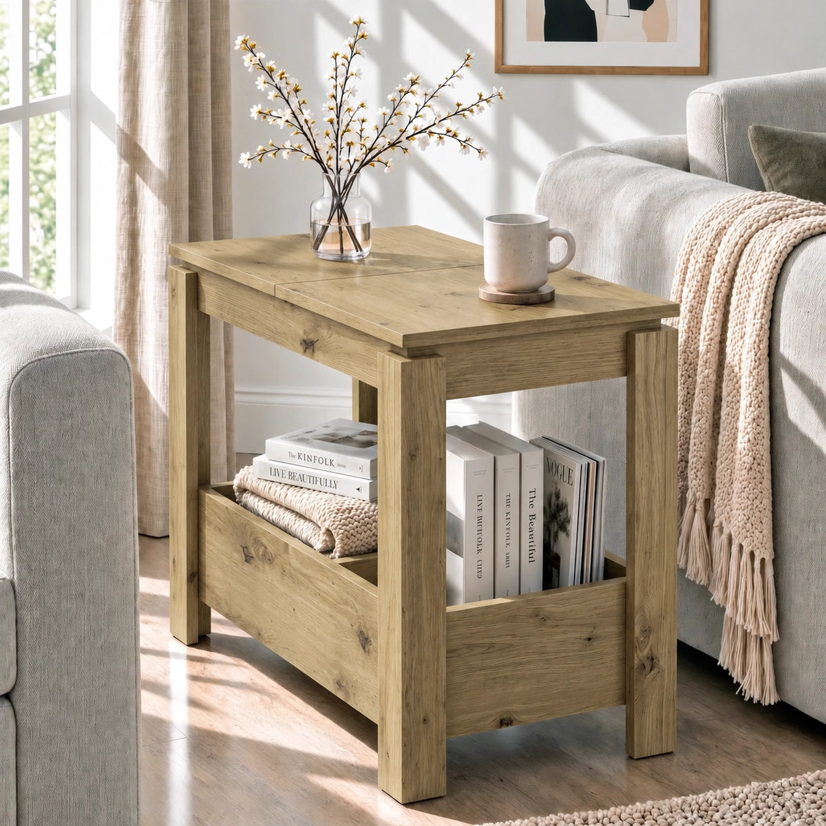 [Oak] Angled side table view with a cup and blossom vase on the closed top, books below and a sofa alongside.