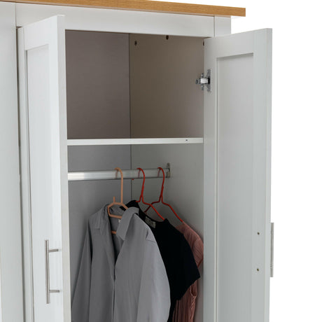 Inside of white wardrobe showing a hanging rail with clothes, including a top shelf.