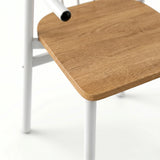 [Oak] Torvi chair close-up of rounded oak seat pad resting on white powder-coated metal frame legs