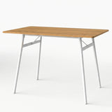 [Oak] Torvi dining table alone on white background showing warm oak-effect MDF top and white metal angled legs with cross-brace frame detail