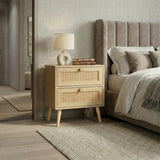 [Oak] Wovena rattan bedside placed next to a grey upholstered bed with lamp and books on top