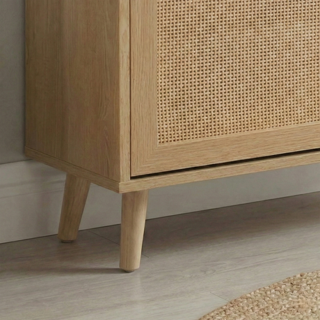 [Oak] Wovena shoe cabinet close-up of natural tapered mid-century leg detail and lower rattan panel corner showing light wood grain texture finish on pale floor
