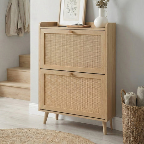 [Oak] Wovena shoe cabinet three-quarter angle view with closed rattan panel drawers, tapered legs, and top shelf styled with botanical print, vase, and keys tray
