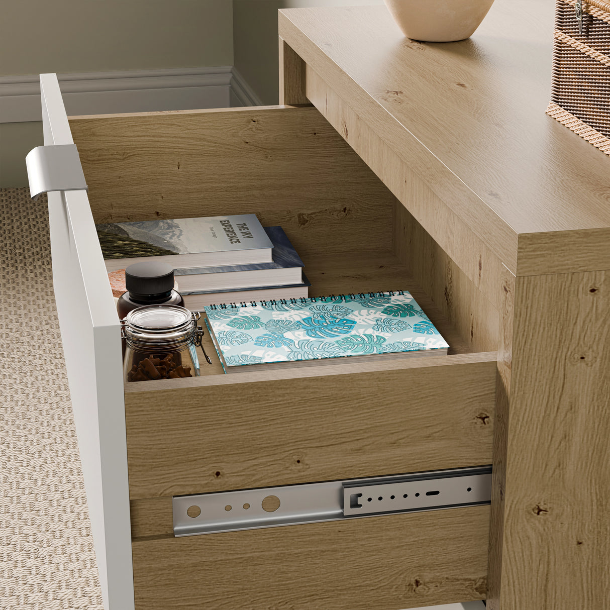 Close up of an open drawers for bedroom in white and wood finish showing books, a notebook, and small jars
