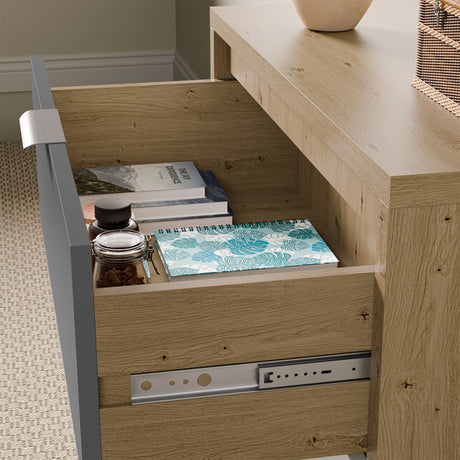 Close-up shot of a wide chest of drawers with one drawer open, showing notebooks and small jars inside