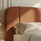 Close view of textured orange upholstery with softly curved cushioned headrest in a panelled wall room 