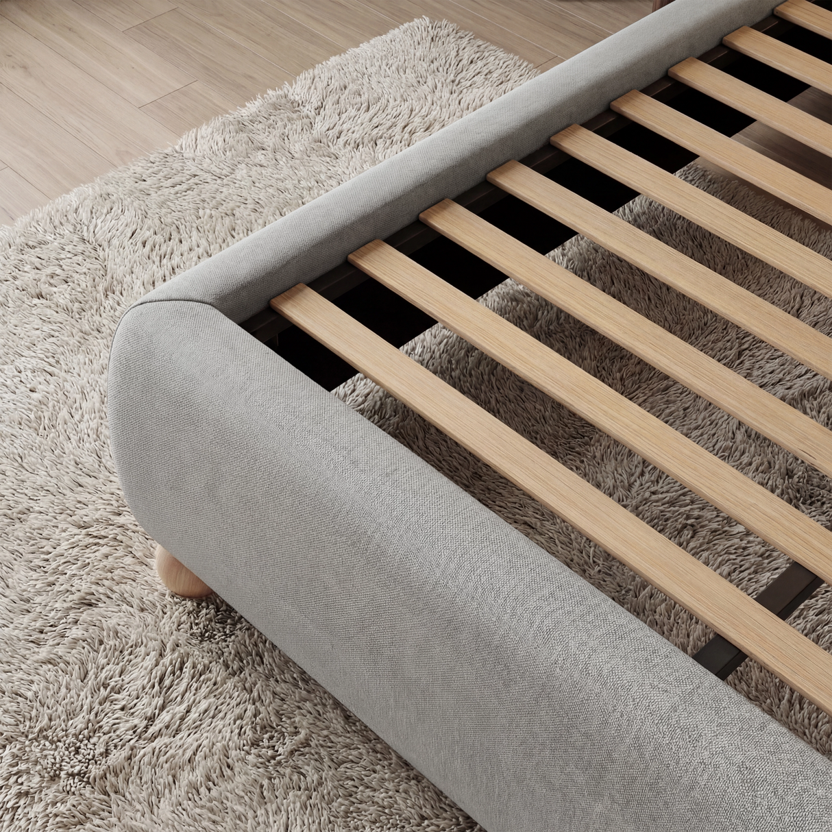 [Double | Grey] Wooden slats inside grey fabric double ottoman bed frame shown from side, above pale cream rug
