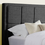 Close-up of dark grey tufted headboard with soft pillows and cozy bedding.