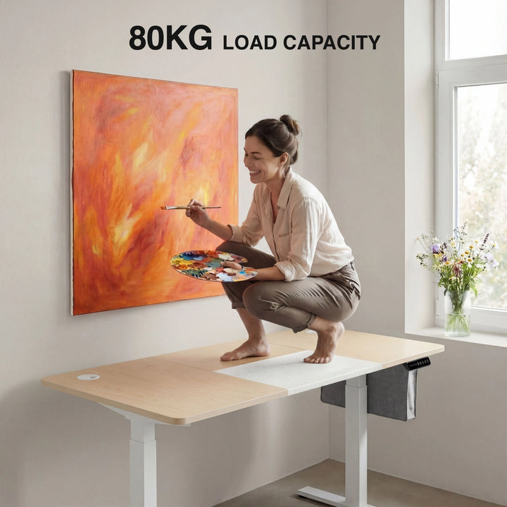 [120cm x 60cm] pine standing desk 120cm strength shot, painter kneeling on desk surface working on a large orange artwork