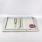 Pink foldable laptop desk with adjustable height, providing comfort and portability for use in bed, on the sofa, or any relaxed setting.