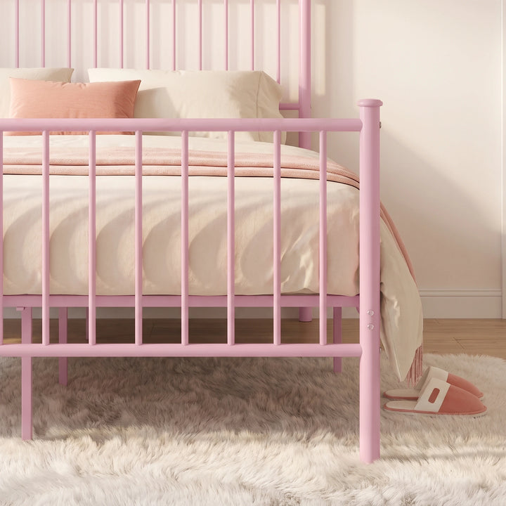 [Pink | King] Footboard detail showing vertical bars, a capped post, fixing bolts, centre leg, cream bedding, and slippers.