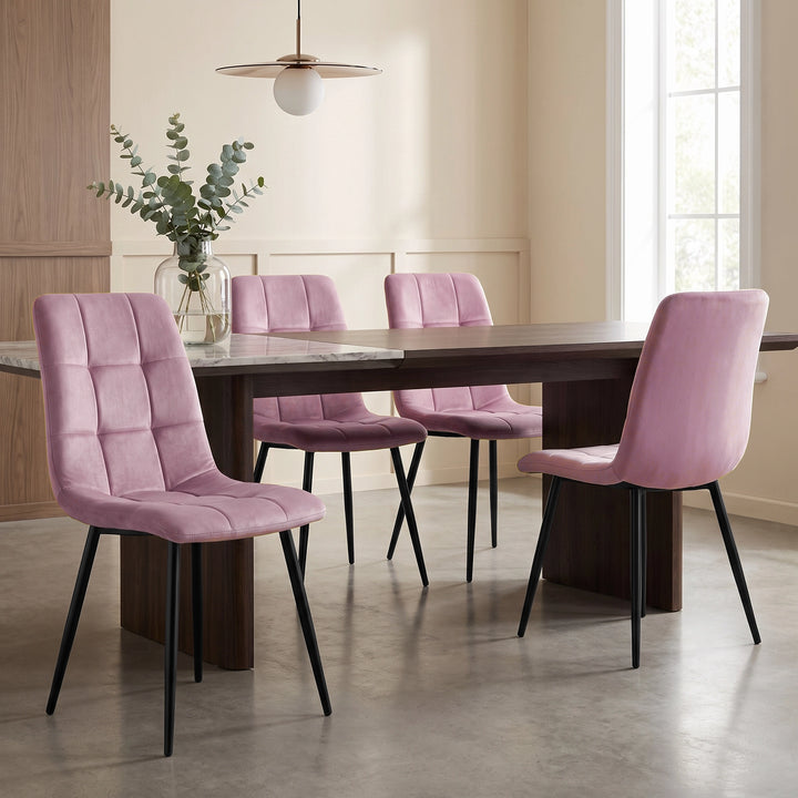 [Pink | Set of 4] Velvet dining chairs at a rectangular table, with curved tufted backs, armless seats and black metal legs.