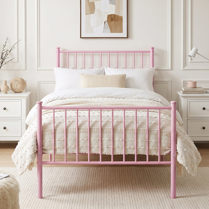 [Pink | Single] Front view of metal single bed with white bedding, beige throw, bar ends, centre leg, nightstands & wall art.