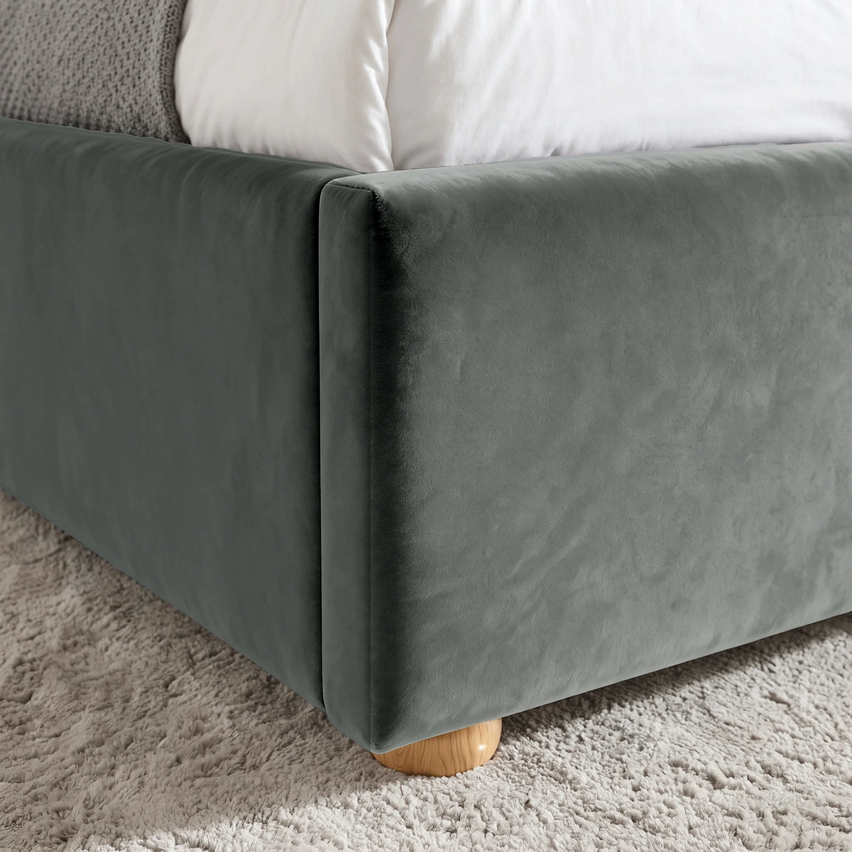 [Double | Grey] Close-up view of the rounded wooden foot and upholstered corner of the Plush Velvet Ottoman Double Bed Frame