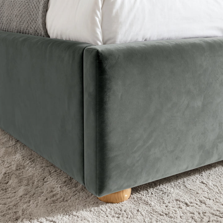 [Double | Grey] Close-up view of the rounded wooden foot and upholstered corner of the Plush Velvet Ottoman Double Bed Frame